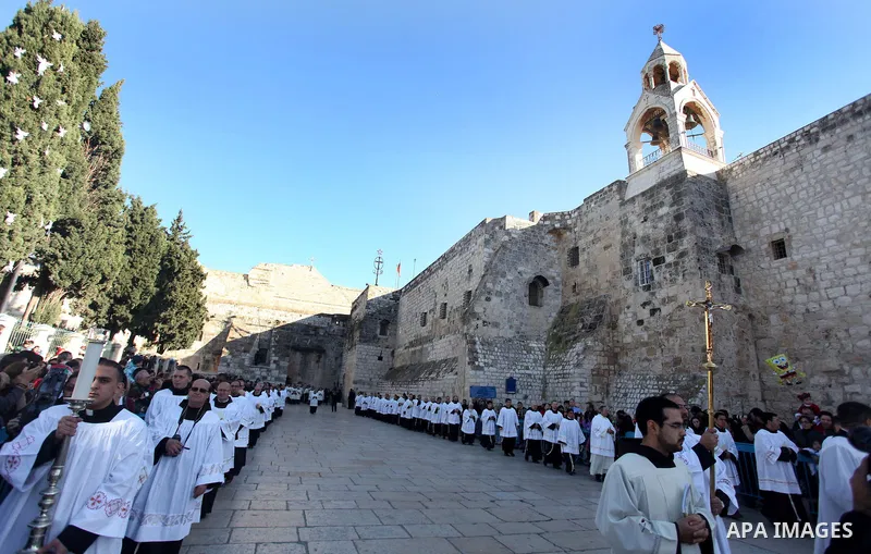 A member of the clergy holds a cross as he waits for the arrival of the Latin Patriarch of Jerusalem Fouad Twal outside the Church of the Nativity, the site revered as the birthplace of Jesus, in the West Bank city of Be...