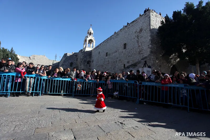 Palestinians wait for the arrival of the Latin Patriarch of Jerusalem Fouad Twal outside the Church of the Nativity, the site revered as the birthplace of Jesus, in the West Bank city of Bethlehem December 24, 2012. Phot...