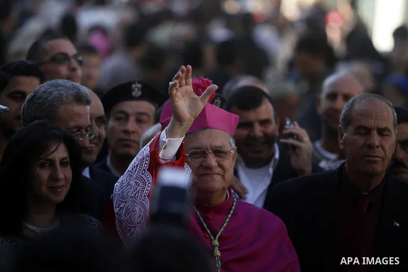 The Latin Patriarch of Jerusalem Fuad Twal, the head of the Roman Catholic Church in the Holy Land, waves to the crowds as he arrives in the West Bank city of Bethlehem after crossing Israel's separation barrier on Decem...
