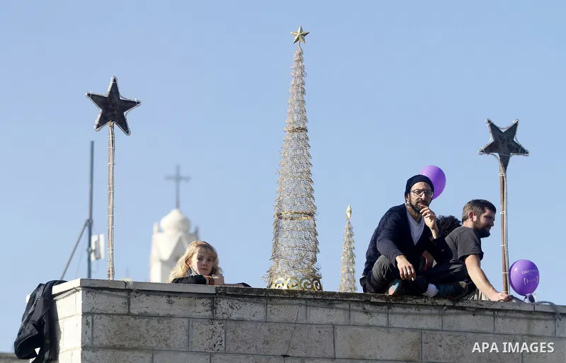 Palestinians wait for the arrival of the Latin Patriarch of Jerusalem Fouad Twal outside the Church of the Nativity, the site revered as the birthplace of Jesus, in the West Bank city of Bethlehem December 24, 2012. Phot...