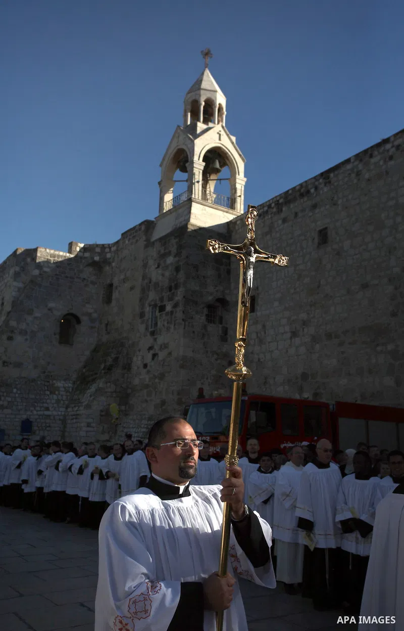A member of the clergy holds a cross as he waits for the arrival of the Latin Patriarch of Jerusalem Fouad Twal outside the Church of the Nativity, the site revered as the birthplace of Jesus, in the West Bank city of Be...