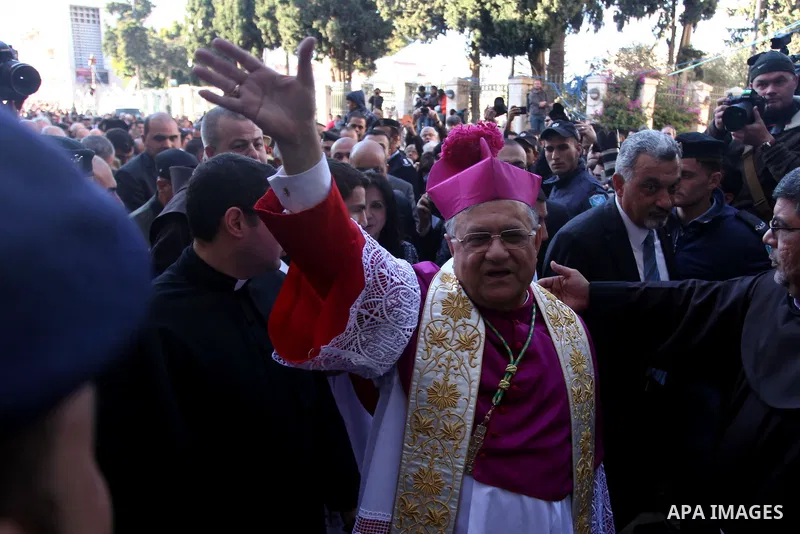 The Latin Patriarch of Jerusalem Fuad Twal, the head of the Roman Catholic Church in the Holy Land, waves to the crowds as he arrives in the West Bank city of Bethlehem after crossing Israel's separation barrier on Decem...
