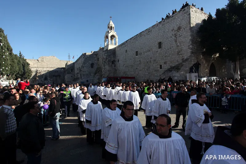 Members of the clergy wait for the arrival of the Latin Patriarch of Jerusalem Fouad Twal outside the Church of the Nativity, the site revered as the birthplace of Jesus, in the West Bank city of Bethlehem December 24, 2...