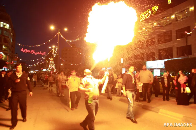 A Palestinian man spews fire from his mouth as he attends the Christmas celebrations in the West Bank city of Nablus on Dec. 24, 2012. Photo by Nedal Eshtayah