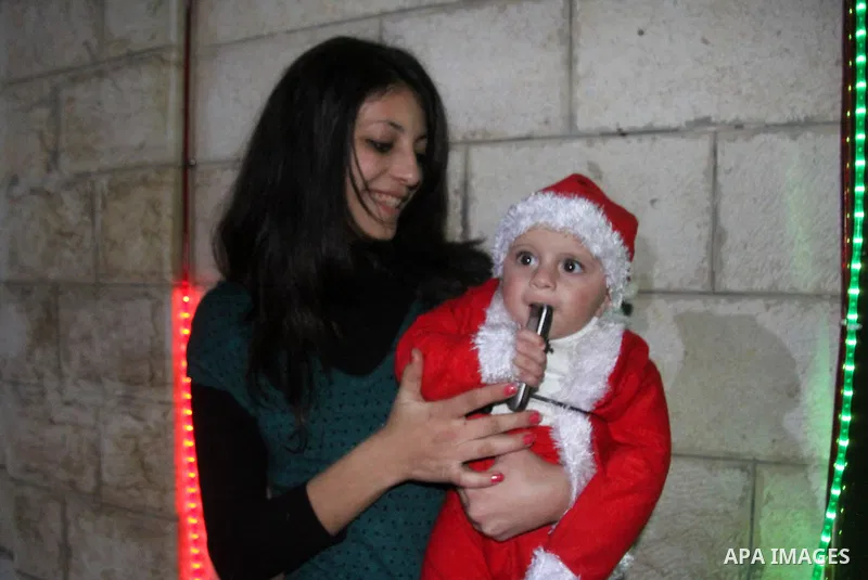 A Palestinian Christian with her son at a church of Deir Latin, during Christmas celebrations in in Gaza city, on December 24, 2012. Photo by Ezz al-Zanoon