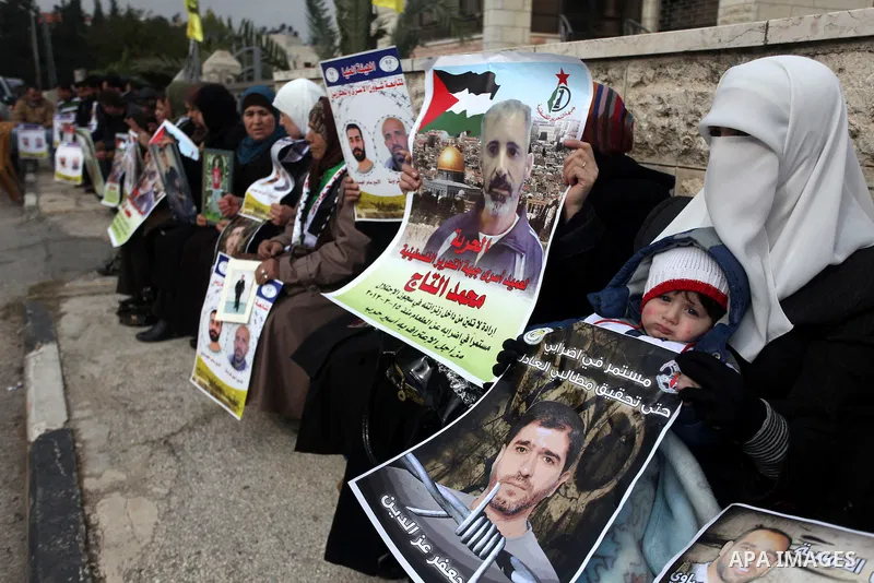 Palestinians hold pictures of prisoners held in Israeli jails during a sit-in outside the Red Crescent offices near the West Bank city of Ramallah, in solidarity with hunger-striking detainees held by Israel to demand th...