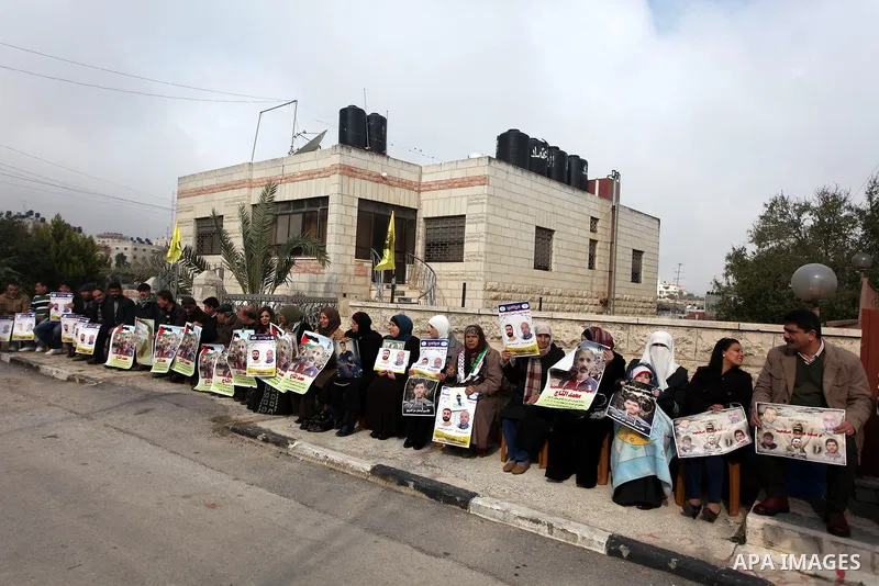 Palestinians hold pictures of prisoners held in Israeli jails during a sit-in outside the Red Crescent offices near the West Bank city of Ramallah, in solidarity with hunger-striking detainees held by Israel to demand th...