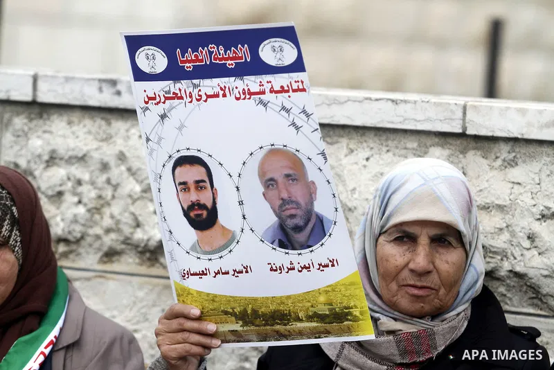 Palestinians hold pictures of prisoners held in Israeli jails during a sit-in outside the Red Crescent offices near the West Bank city of Ramallah, in solidarity with hunger-striking detainees held by Israel to demand th...