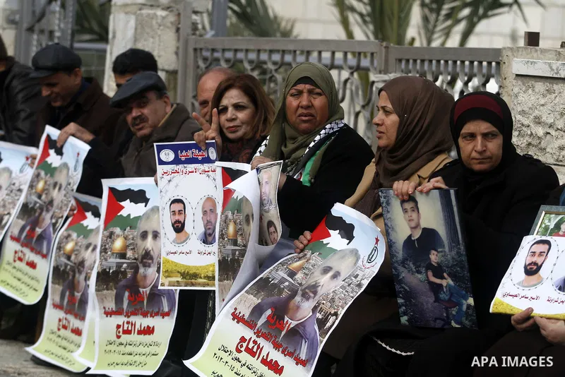 Palestinians hold pictures of prisoners held in Israeli jails during a sit-in outside the Red Crescent offices near the West Bank city of Ramallah, in solidarity with hunger-striking detainees held by Israel to demand th...
