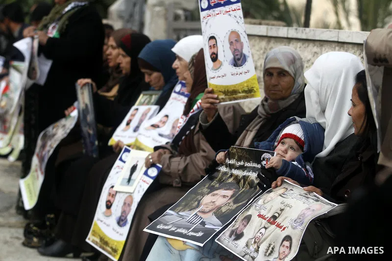 Palestinians hold pictures of prisoners held in Israeli jails during a sit-in outside the Red Crescent offices near the West Bank city of Ramallah, in solidarity with hunger-striking detainees held by Israel to demand th...