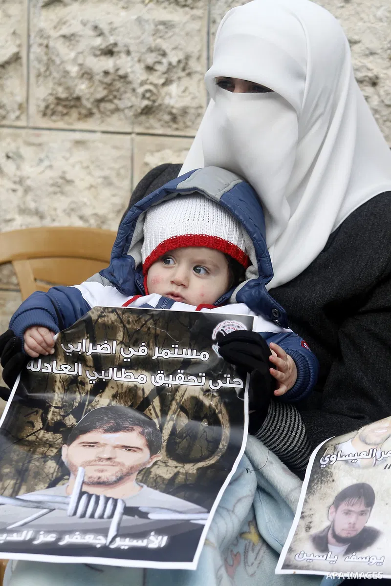 Palestinians hold pictures of prisoners held in Israeli jails during a sit-in outside the Red Crescent offices near the West Bank city of Ramallah, in solidarity with hunger-striking detainees held by Israel to demand th...