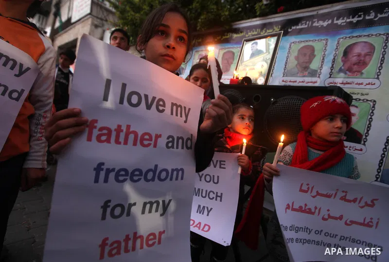 Palestinian children hold placards and candles during a candlelight rally in solidarity with hunger-striking detainees held by Israel in Gaza city to demand their release from detention without trial. December 25, 2012....