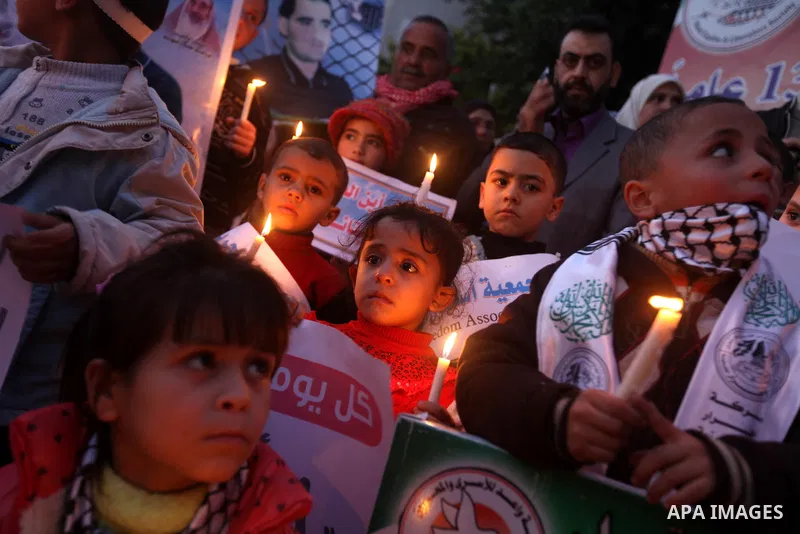 Palestinian children hold placards and candles during a candlelight rally in solidarity with hunger-striking detainees held by Israel in Gaza city to demand their release from detention without trial. December 25, 2012....
