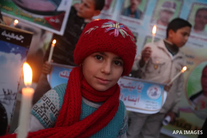 Palestinian children hold placards and candles during a candlelight rally in solidarity with hunger-striking detainees held by Israel in Gaza city to demand their release from detention without trial. December 25, 2012....