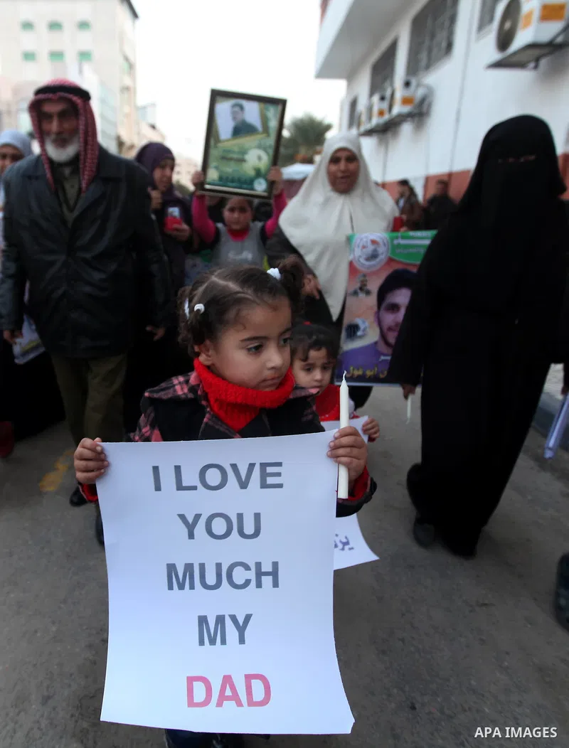Palestinian children hold placards and candles during a candlelight rally in solidarity with hunger-striking detainees held by Israel in Gaza city to demand their release from detention without trial. December 25, 2012....