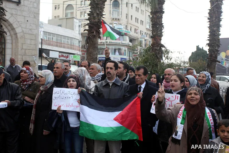 Palestinians hold placards and their national flags during a demonstration in the West Bank city of Ramallah calling for an end in the political division and commitment to the reconciliation agreement between rival Pales...