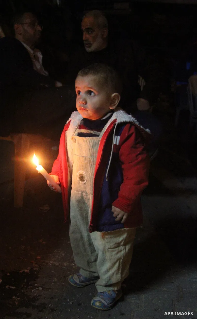 Palestinian children hold candles during a candlelight vigil in front of Red Cross offices, solidarity with hunger-striking detainees held by Israel in Gaza city to demand their release from detention without trial. Dece...
