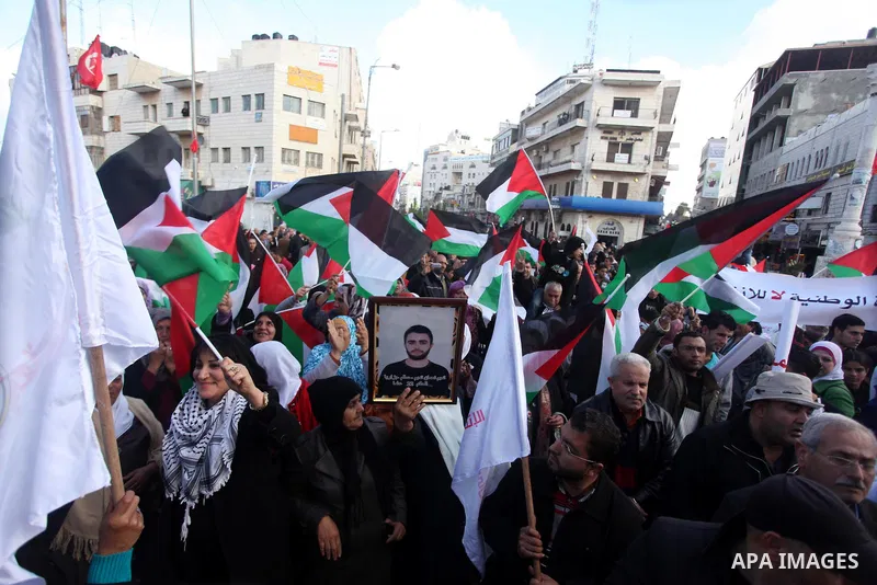 Palestinians hold placards and their national flags during a demonstration in the West Bank city of Ramallah calling for an end in the political division and commitment to the reconciliation agreement between rival Pales...