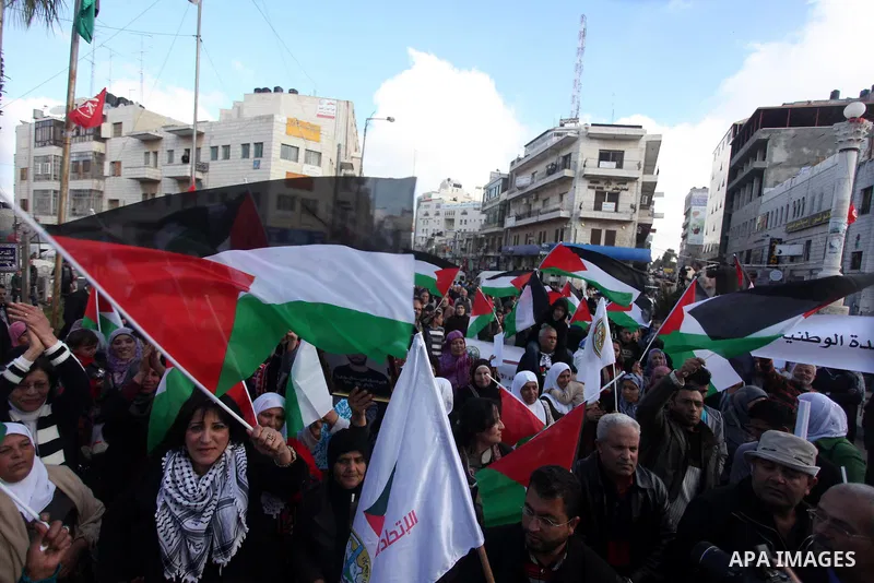 Palestinians hold placards and their national flags during a demonstration in the West Bank city of Ramallah calling for an end in the political division and commitment to the reconciliation agreement between rival Pales...