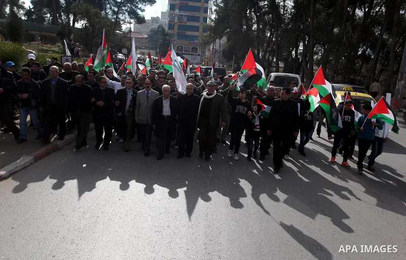Palestinians hold placards and their national flags during a demonstration in the West Bank city of Ramallah calling for an end in the political division and commitment to the reconciliation agreement between rival Pales...