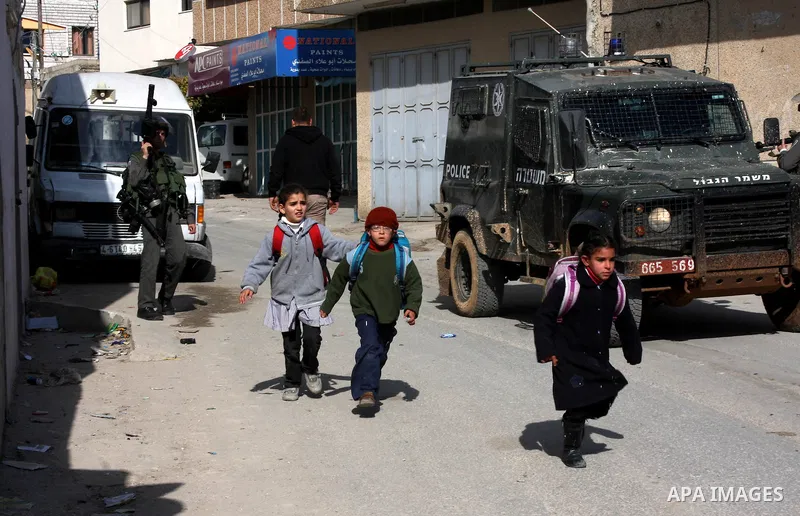 A Palestinian schoolchildrenl passes Israeli soldiers, during a search carried out by Israeli soldiers after they raid the village of Urif, near Nablus, West Bank, 27 December 2012. Israeli soldiers raided the village af...