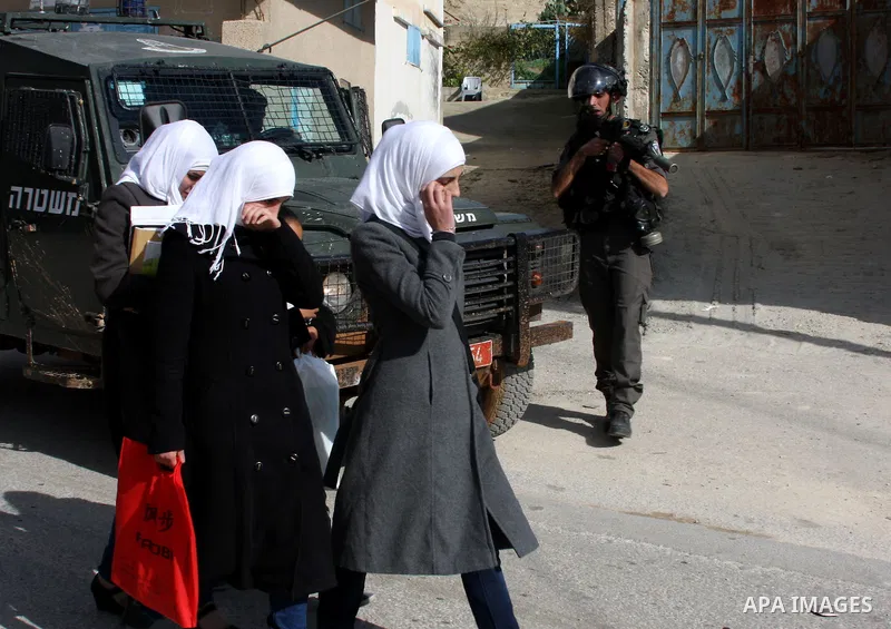 Palestinian schoolgirls pass an Israeli soldier, during a search carried out by Israeli soldiers after they raid the village of Urif, near Nablus, West Bank, 27 December 2012. Israeli soldiers raided the village after cl...