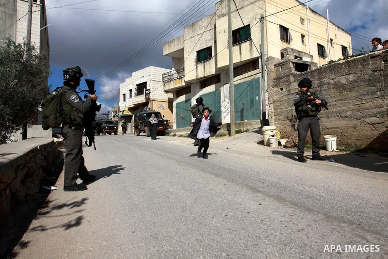 A Palestinian schoolgirl passes Israeli soldiers, during a search carried out by Israeli soldiers after they raid the village of Urif, near Nablus, West Bank, 27 December 2012. Israeli soldiers raided the village after c...