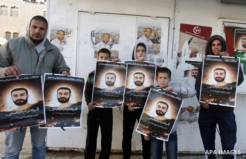 Palestinian protesters hold portraits of Samer Issawi, a Palestinian prisoner held in an Israeli jail and on hunger strike since August 1, during a solidarity sit-in outside the Red Cross offices in Jerusalem, on Dec. 27...