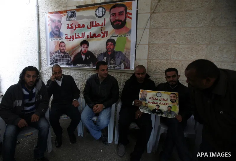 Palestinian protesters hold portraits of Samer Issawi, a Palestinian prisoner held in an Israeli jail and on hunger strike since August 1, during a solidarity sit-in outside the Red Cross offices in Jerusalem, on Dec. 27...