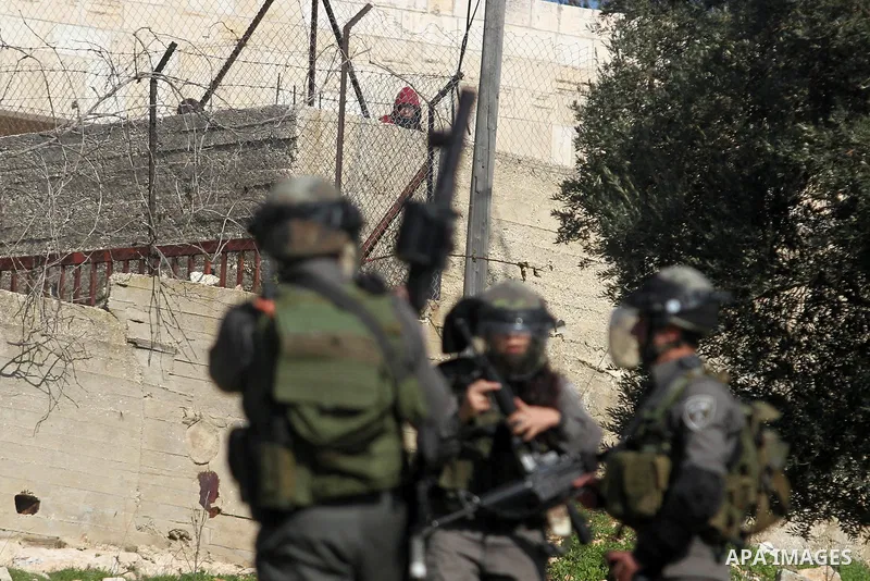 A Palestinian stone-thrower looks at Israeli security officers during clashes at a protest against Jewish settlements, in the West Bank village of Nabi Saleh, near Ramallah December 28, 2012. Photo by Issam Rimawi