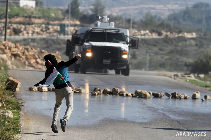 A Palestinian protester throws a stone at Israeli security officers during clashes at a protest against Jewish settlements, in the West Bank village of Nabi Saleh, near Ramallah December 28, 2012. Photo by Issam Rimawi