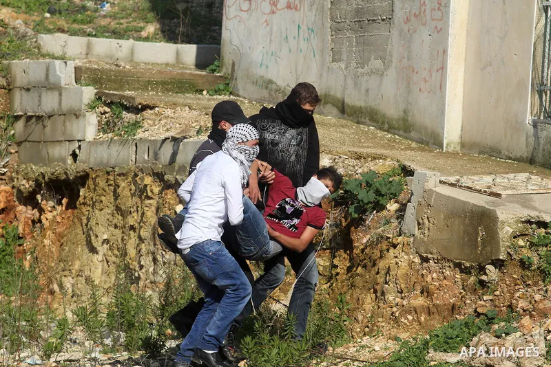 Palestinian stone-throwers carry an injured protester shot by Israeli security officers during clashes at a protest against Jewish settlements, in the West Bank village of Nabi Saleh, near Ramallah December 28, 2012. Pho...