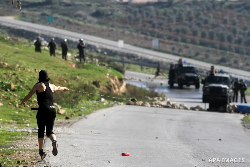 A Palestinian protester uses a sling to throw stones at Israeli security officers during clashes at a protest against Jewish settlements, in the West Bank village of Nabi Saleh, near Ramallah December 28, 2012. Photo by...