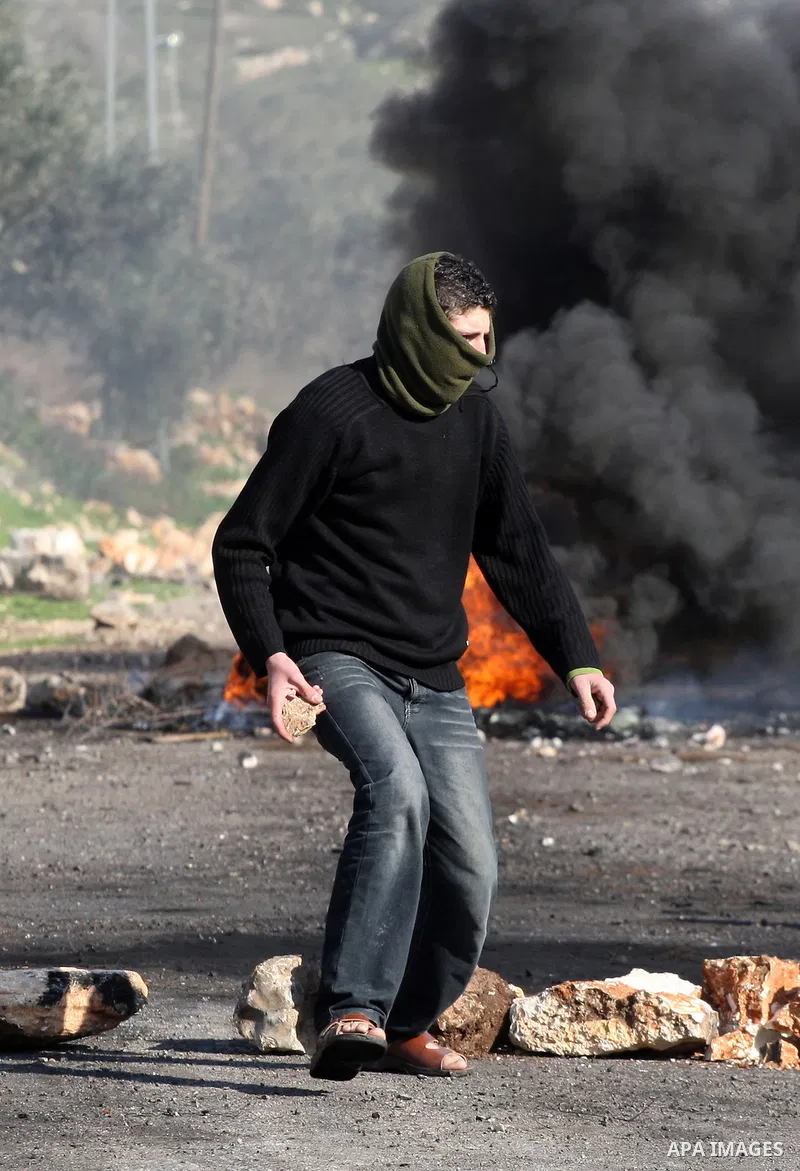 A Palestinian demonstrator throws stones at Israeli soldiers during clashes at the weekly protest against the Jewish settlement of Qadomem, near Nablus, West Bank, 28 December 2012. According to Palestinian sources, five...