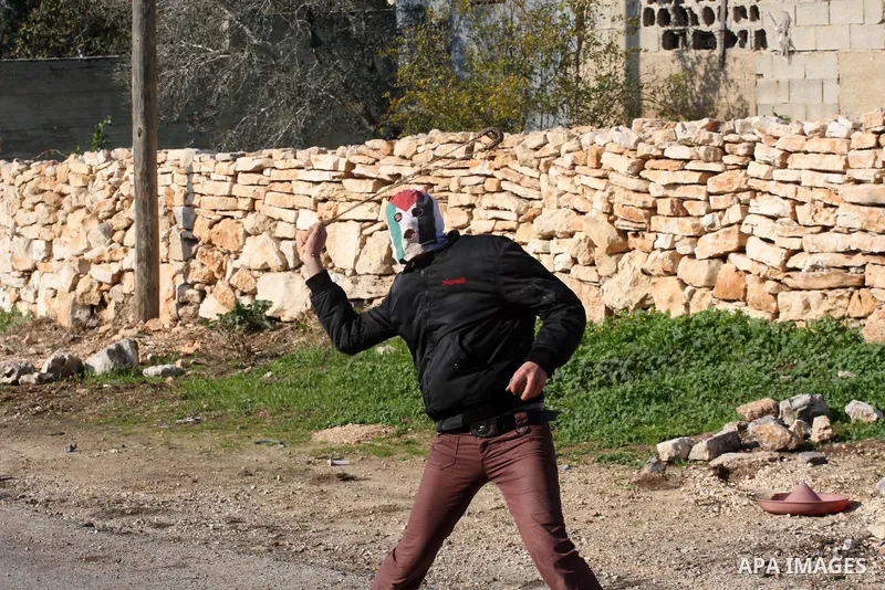A Palestinian demonstrator throws stones at Israeli soldiers during clashes at the weekly protest against the Jewish settlement of Qadomem, near Nablus, West Bank, 28 December 2012. According to Palestinian sources, five...