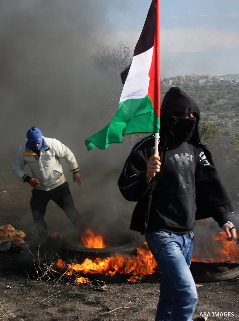 A Palestinian demonstrator burns a tire during clashes at the weekly protest against the Jewish settlement of Qadomem, near Nablus, West Bank, 28 December 2012. According to Palestinian sources, five demonstrators were w...