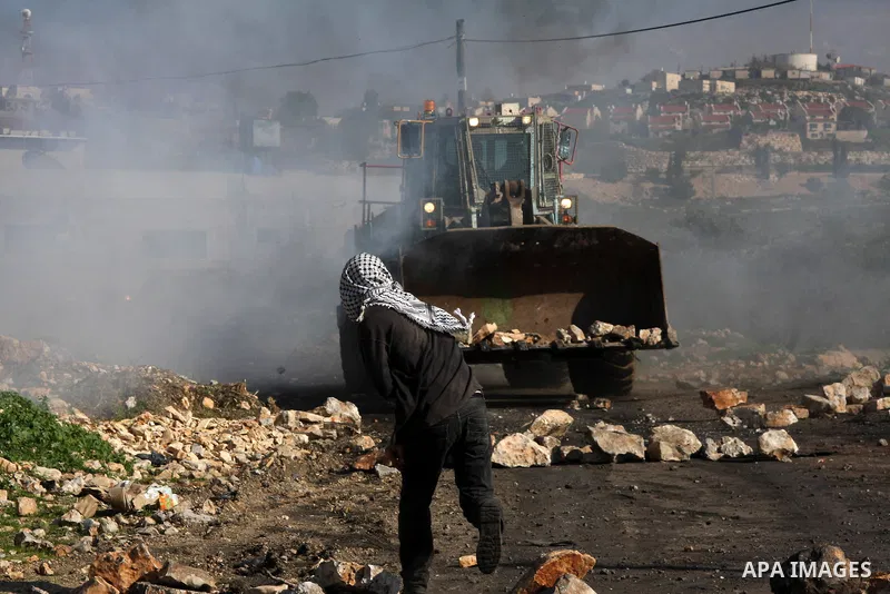 A Palestinian demonstrator throws stones at an Israeli bulldozer during clashes at the weekly protest against the Jewish settlement of Qadomem, near Nablus, West Bank, 28 December 2012. According to Palestinian sources,...