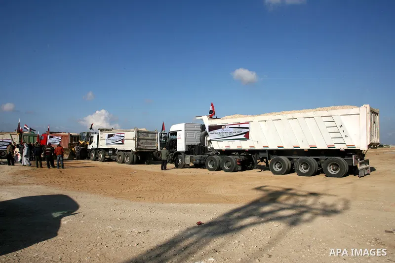 Palestinian men stand near trucks of supplying raw materials of Qatari grant projects in Rafah crossing in the southern Gaza Strip. Egypt allowed access supplying raw materials of Qatari grant projects Through the Rafah...