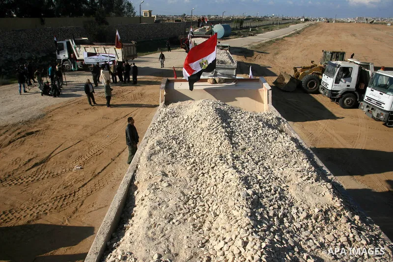 Palestinian men stand near trucks of supplying raw materials of Qatari grant projects in Rafah crossing in the southern Gaza Strip. Egypt allowed access supplying raw materials of Qatari grant projects Through the Rafah...