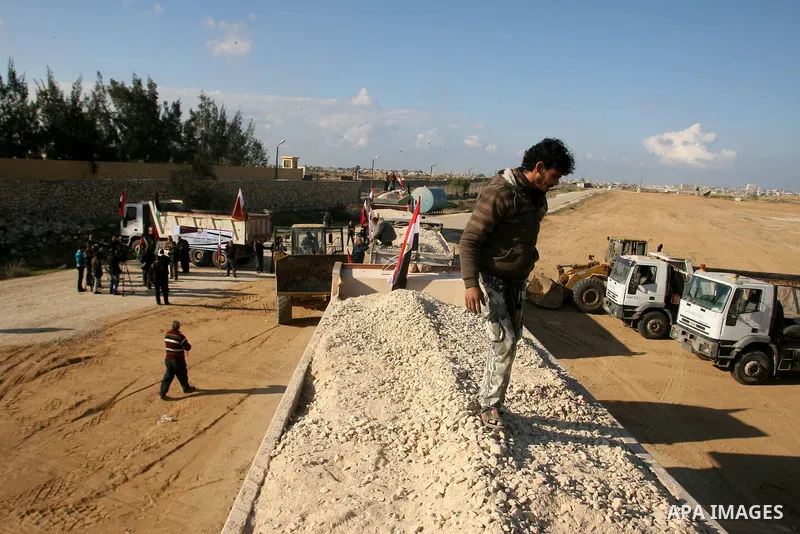 Palestinian men stand near trucks of supplying raw materials of Qatari grant projects in Rafah crossing in the southern Gaza Strip. Egypt allowed access supplying raw materials of Qatari grant projects Through the Rafah...
