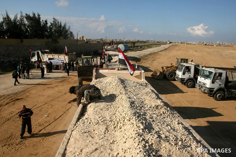 Palestinian men stand near trucks of supplying raw materials of Qatari grant projects in Rafah crossing in the southern Gaza Strip. Egypt allowed access supplying raw materials of Qatari grant projects Through the Rafah...