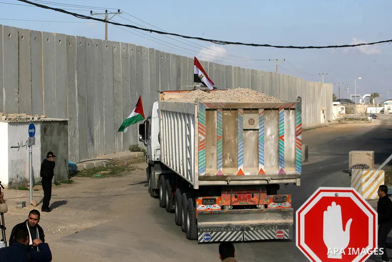 Palestinian men stand near trucks of supplying raw materials of Qatari grant projects in Rafah crossing in the southern Gaza Strip. Egypt allowed access supplying raw materials of Qatari grant projects Through the Rafah...