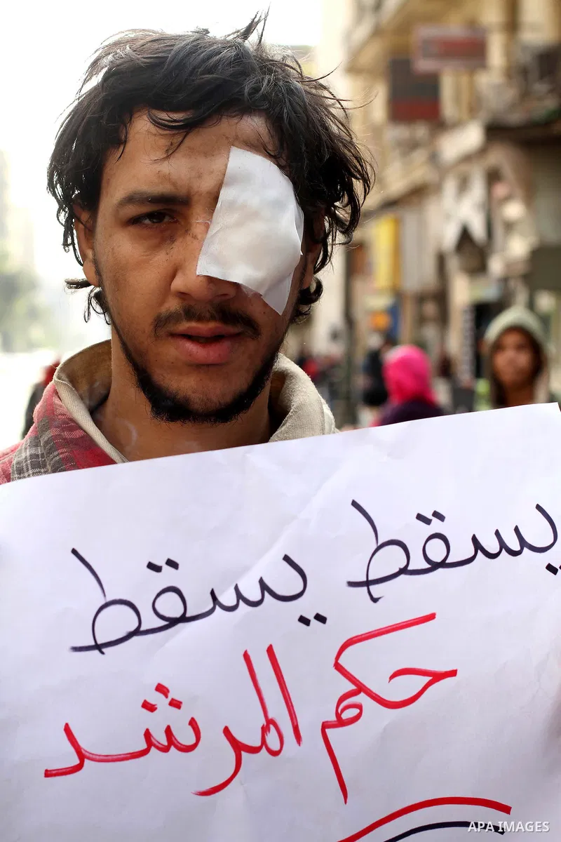 protesters holding signs, and sit in front of police officers near the Shura Council, the upper house of parliament where the Constituent Assembly drafted the country's new constitution, as protesters against Egypt's Pre...