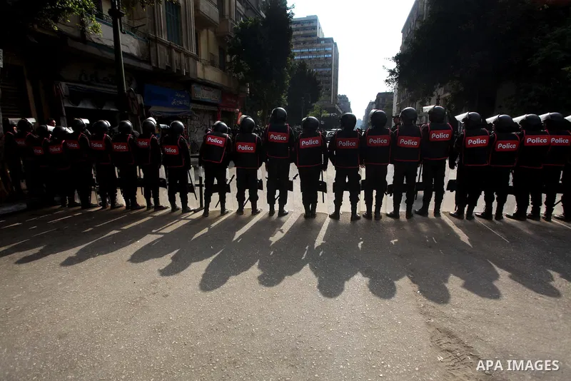Egyptian riot police stand guard outside the Shura Council, the upper house of parliament where the Constituent Assembly drafted the country's new constitution, as protesters against Egypt's President Mohamed Morsi chant...