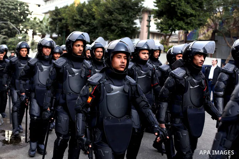 Egyptian riot police stand guard outside the Shura Council, the upper house of parliament where the Constituent Assembly drafted the country's new constitution, as protesters against Egypt's President Mohamed Morsi chant...