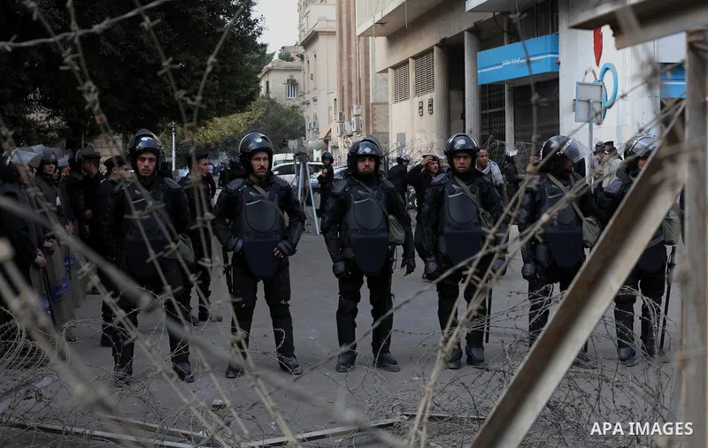 Egyptian riot police stand guard outside the Shura Council, the upper house of parliament where the Constituent Assembly drafted the country's new constitution, as protesters against Egypt's President Mohamed Morsi chant...