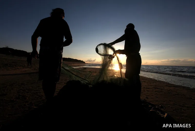 Palestinian fishers prepare to throw their trawl in the sea during sunset on the beach of Gaza city,on December 29, 2012. Photo by Majdi Fathi