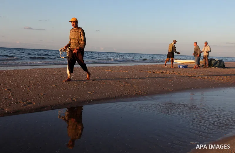 Palestinian fishers prepare to throw their trawl in the sea during sunset on the beach of Gaza city,on December 29, 2012. Photo by Majdi Fathi