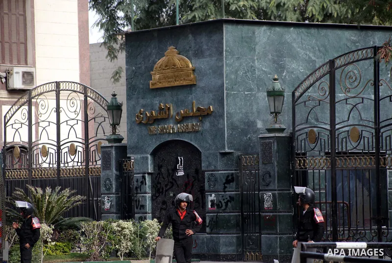 Egyptian riot police stand guard outside the Shura Council, the upper house of parliament where the Constituent Assembly drafted the country's new constitution, as protesters against Egypt's President Mohamed Morsi chant...