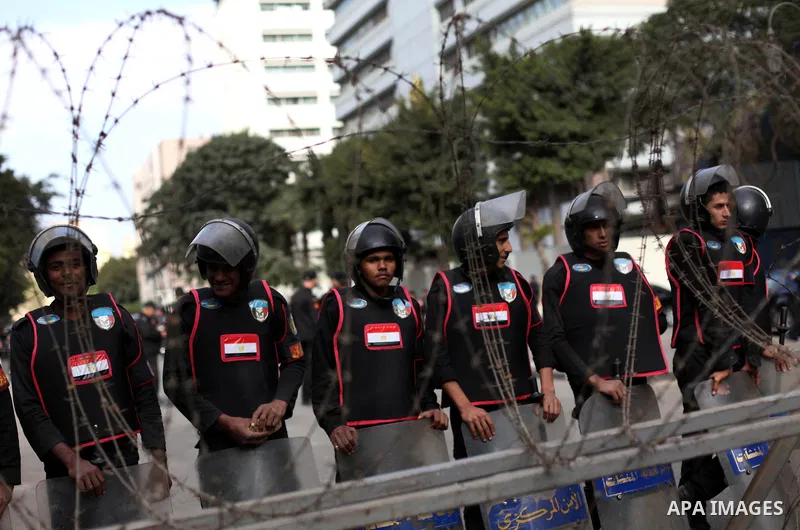 Egyptian riot police stand guard outside the Shura Council, the upper house of parliament where the Constituent Assembly drafted the country's new constitution, as protesters against Egypt's President Mohamed Morsi chant...
